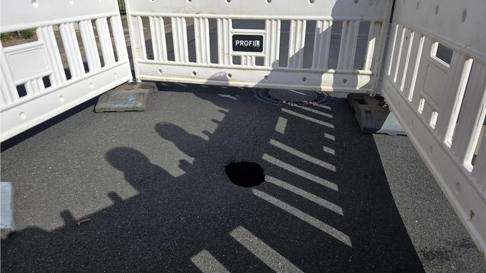 Gibt Rätsel auf: Ein Loch im Asphalt. (Foto: tau)