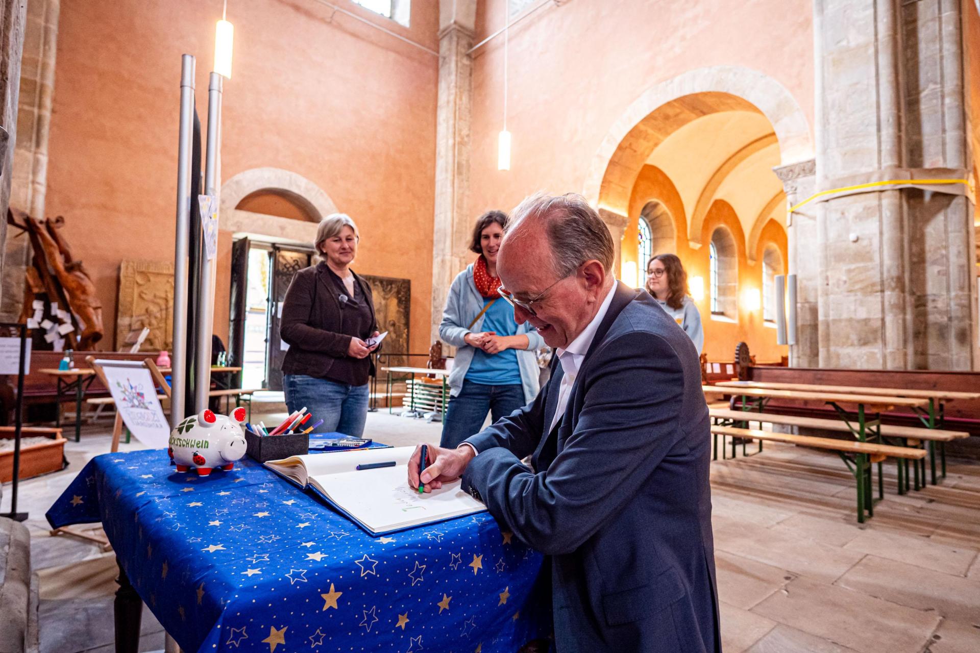 Schreibt ins Gästebuch: Landesbischof Ralf Meister. (Foto: Mirko Bartels)