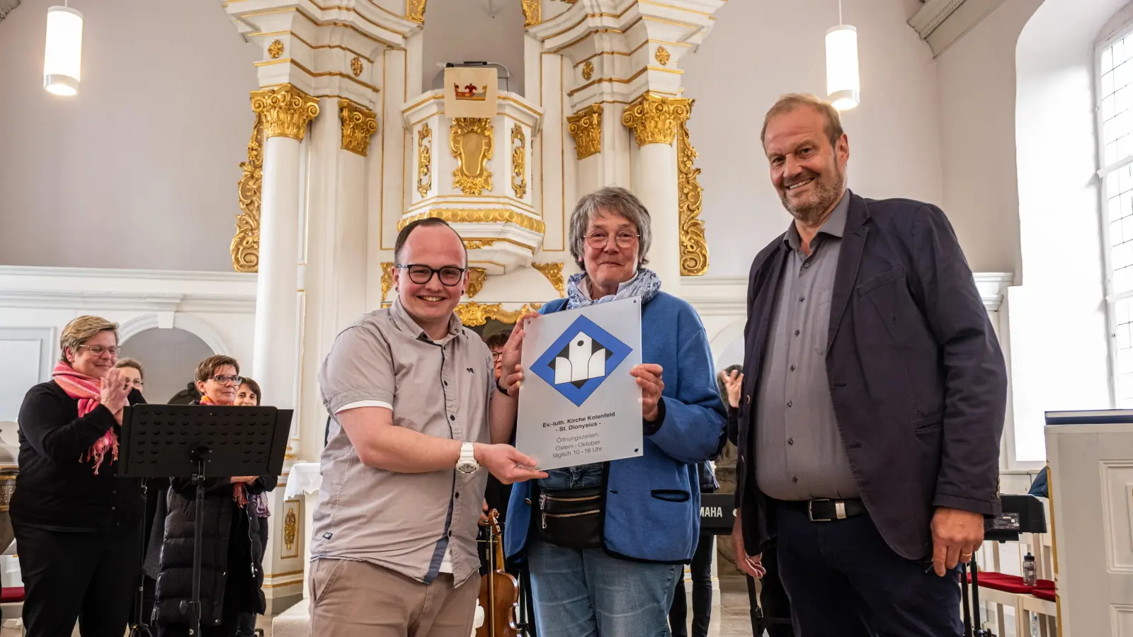 Übergabe der Tafel (v.li.): Tim Jonas Rambeaud und Brigitte Sensch aus dem Kirchenvorstand sowie Diakon Klaus Stemmann. (Foto: privat)
