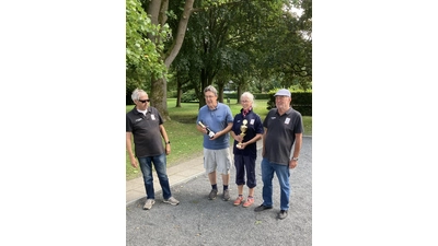 Wolfgang Tadge, stellvertretender Vorsitzender des Boule-Club Stadthagen, übergibt den Pokal an die Vereinsmeister Hans Werner Koller, Christina Stemme und Dieter Sackmann. (Foto: privat)