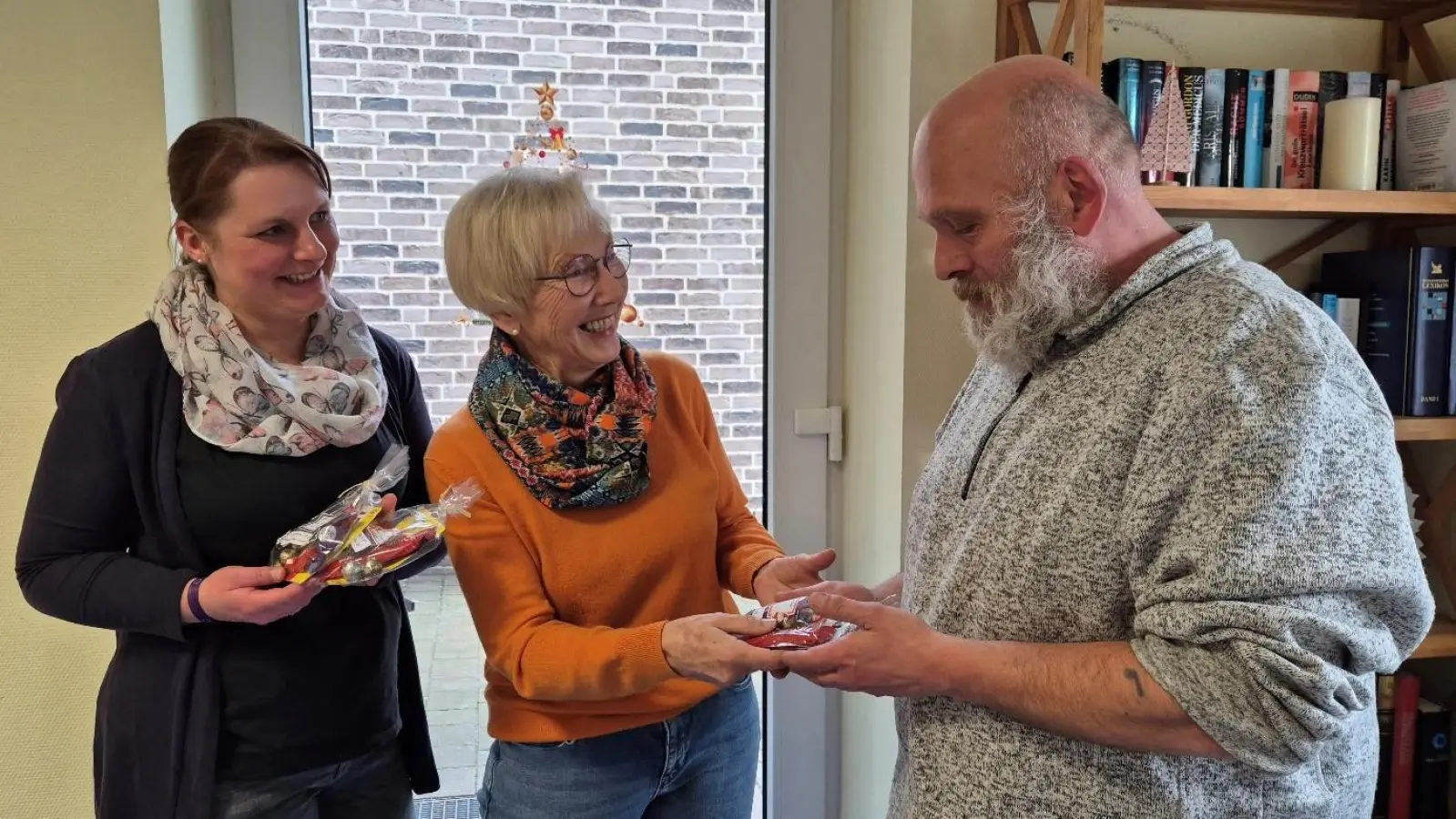 Übergabe der Nikolausgeschenke (v.li.): Simone Läßing (Sozialarbeiterin), Elke Evers (Beisitzerin des Förderkreises und Koordinatorin der ehrenamtlichen Mitarbeitenden) und Lars. (Foto: privat)