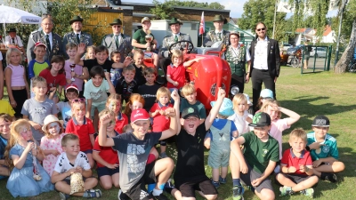 SSG-Vorsitzender Martin Ehlerding sitzt am Lenkrad des frisch lackierten Porsche Junior Baujahr 1959 von Nils Zander mit dem Jüngstenkönig Leopold Rhein (stehend li. auf dem Trecker). Die Kinder bildeten dazu den passenden Rahmen.  (Foto: gi)