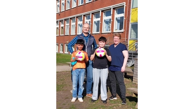 Thorsten Montag vom Weltladen bei der Übergabe der „Catch‘n Serve-Bälle” an Lehrerin Gudrun Raupach und Schüler von der Grundschule Am Sonnenbrink. (Foto: privat)