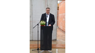 Bernd Gerberding, aufgrund des Regens auf Holzbohlen stehend, begrüßt seine Gäste. (Foto: ab)