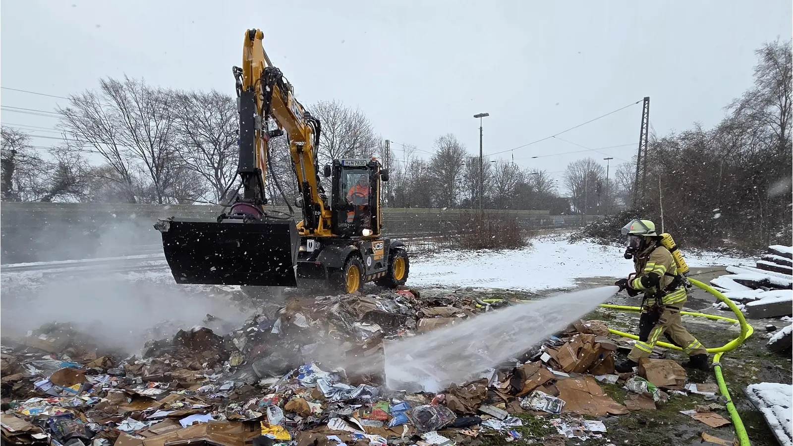 Unterstützt die Löscharbeiten: Ein Bagger des Bauhofes verteilt das gepresste Altpapier. (Foto: Feuerwehr)