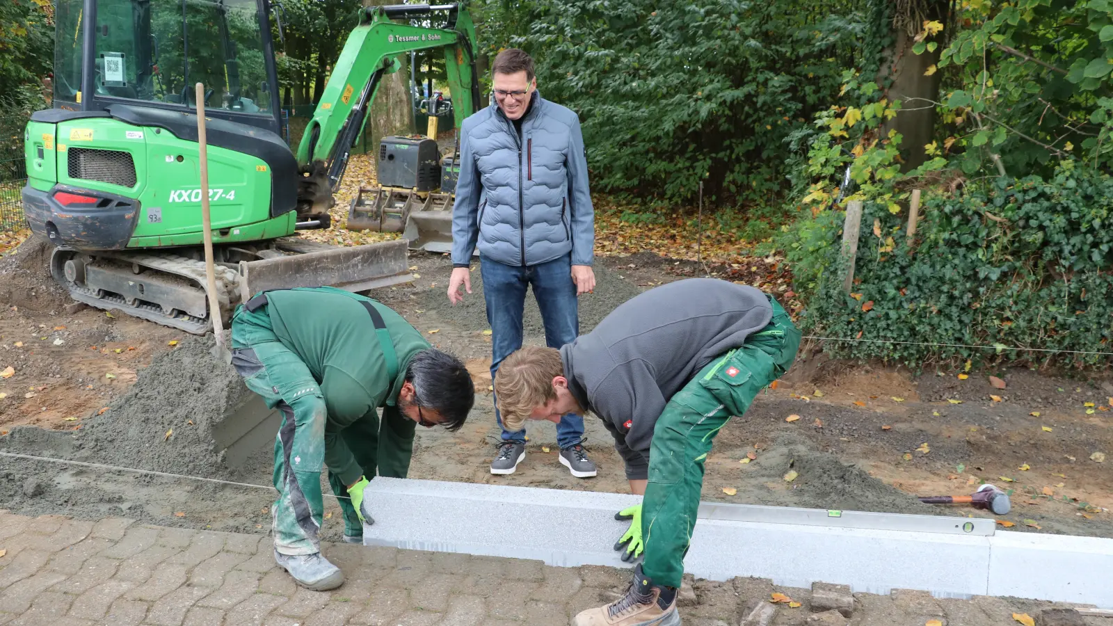 Matthias Waterstradt (Mitte) freut sich über die behindertengerechte Bushaltestelle Niedernfeld. Achmet Sahin (li.) und Sian Stoffer setzen die Bordsteine.  (Foto: gi)