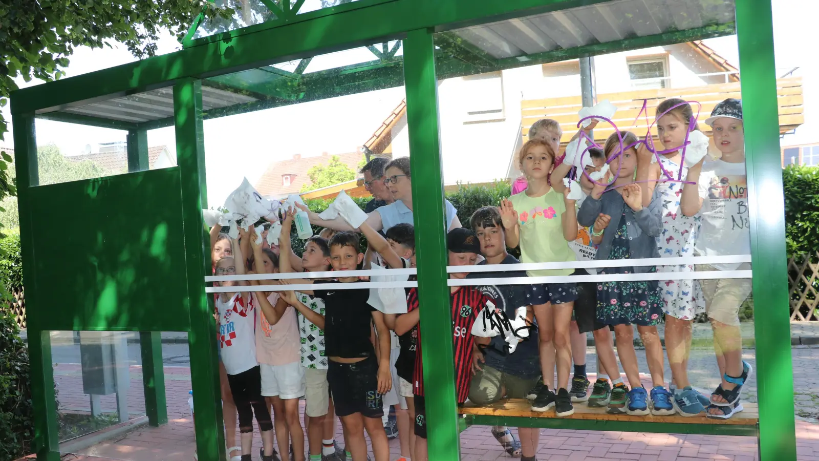 Reinigen „ihr” Buswartehäuschen: Schülerinnen und Schüler, der Hausmeister und die Rektorin der Grundschule. (Foto: gi)