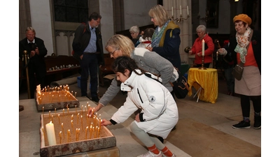 Die Teilnehmer der Interreligiösen Begegnung entzünden Friedenslichter.  (Foto: bb)